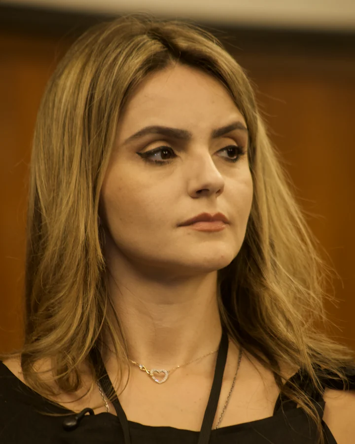 Amanda Vettorazzo, de preto, olhando para o lado